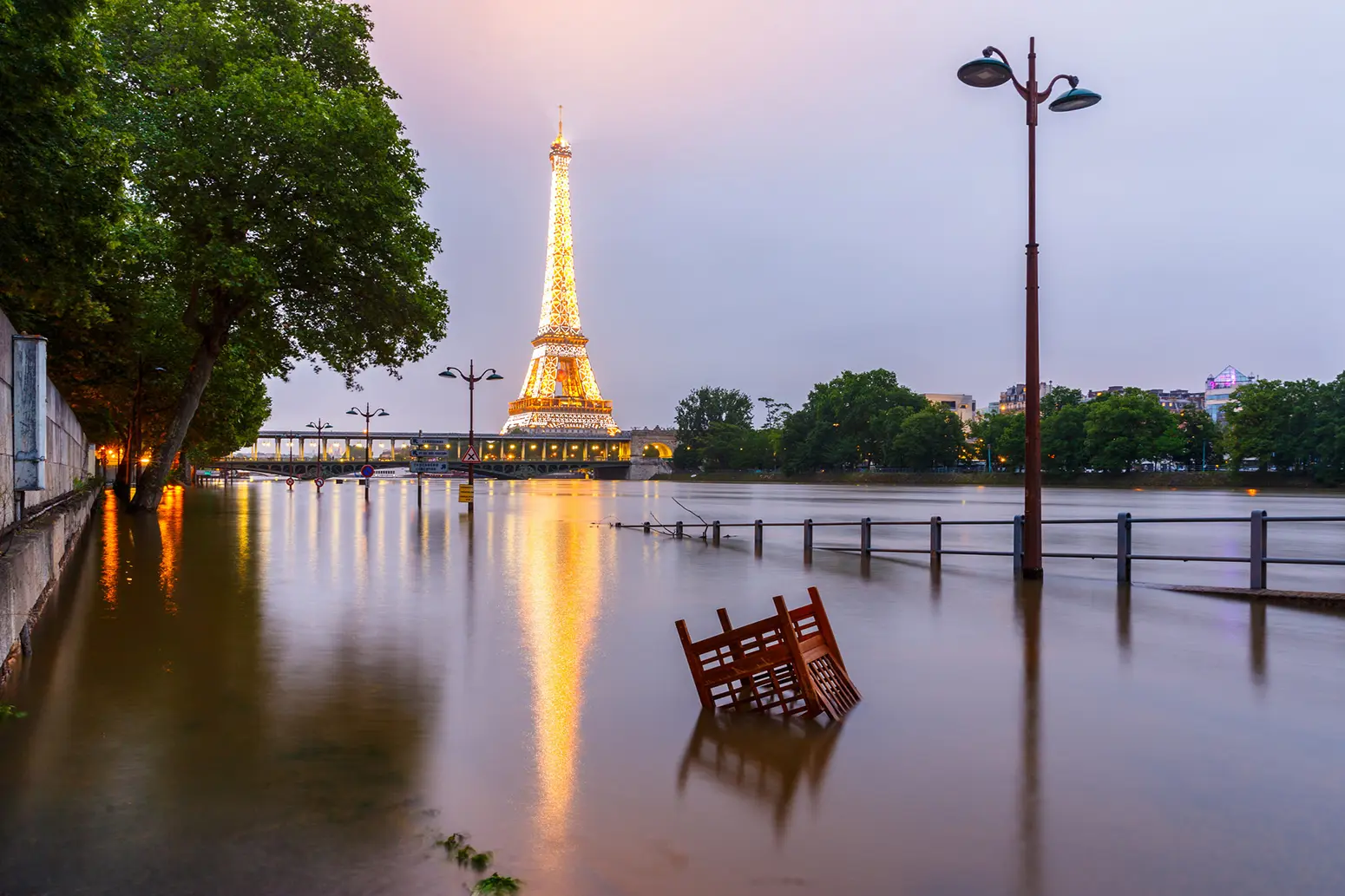 A photo of the River Seine having burst its banks in Paris, with the illuminated Eiffel Tower in the background.